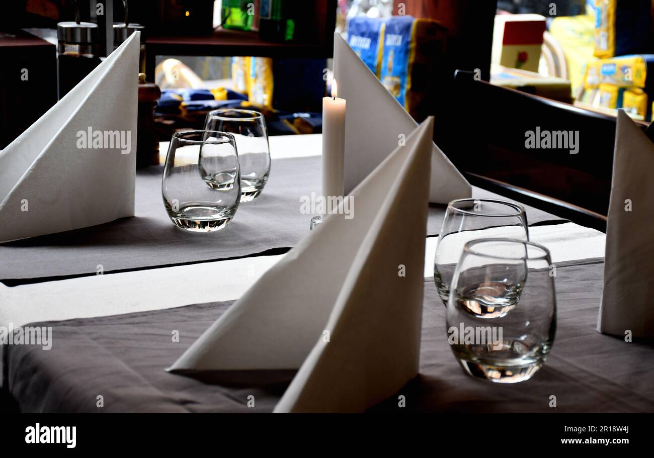 A pristine, white restaurant table with glasses of water and folded napkins Stock Photo