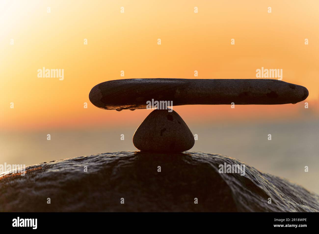 in the balance of power - natural scales of stones by the sea to the orange sunset - symbol photo Stock Photo