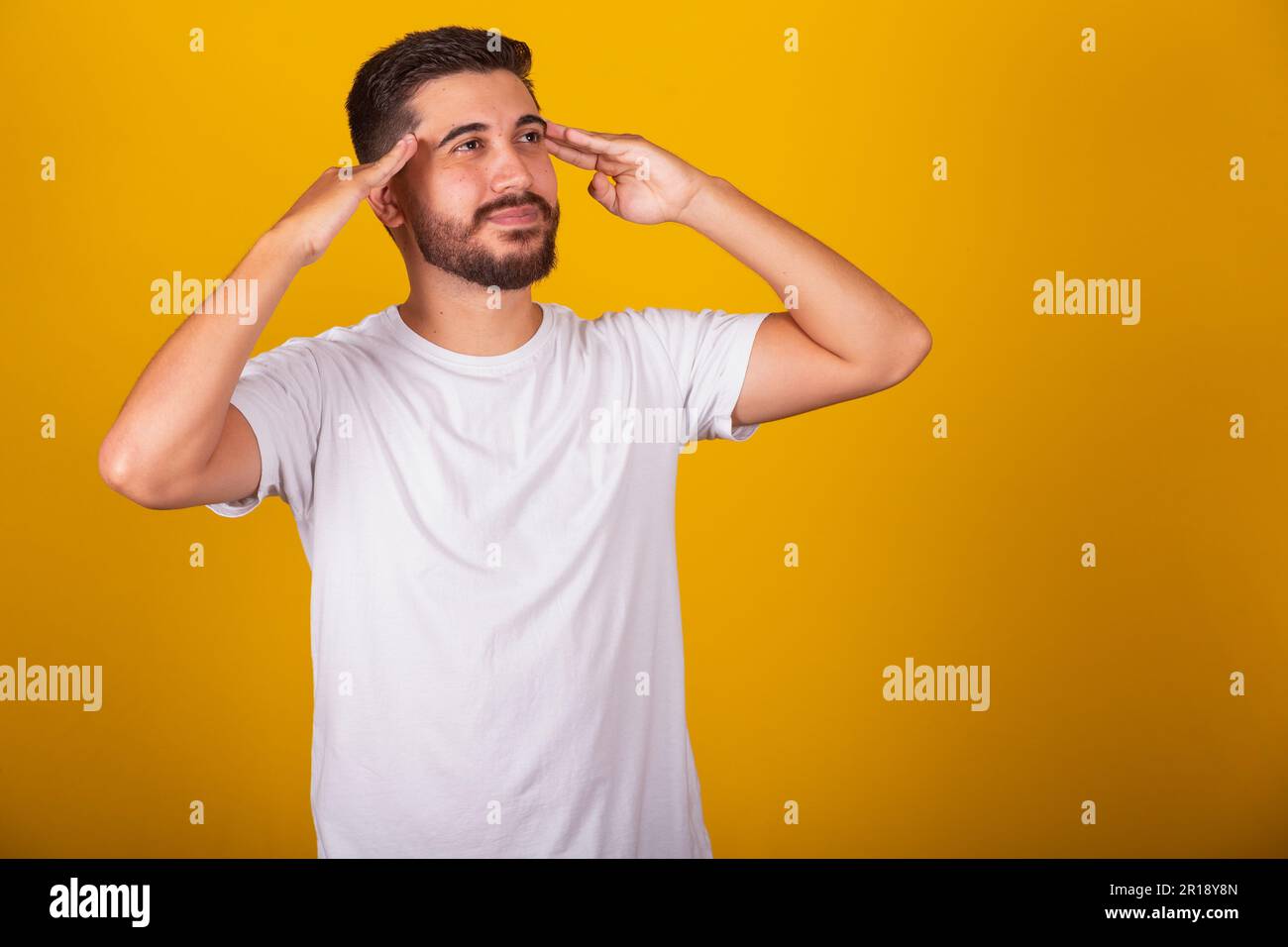 Brazilian Latin American man with hands on forehead and chin representing thought, pensive, doubt, questioning, decision, uncertainty, yellow backgrou Stock Photo