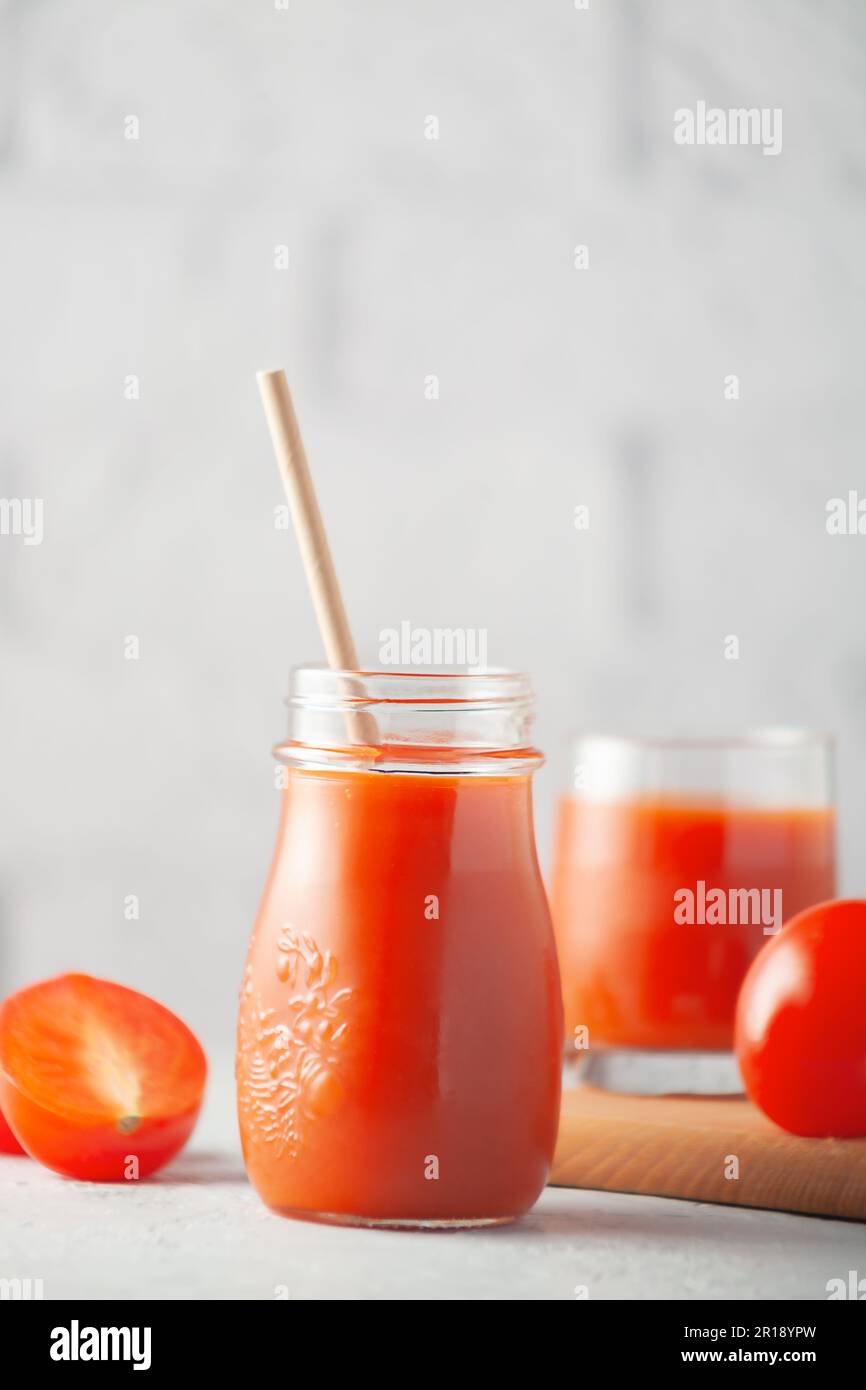 Against the background of a white brick wall, a glass of tomato juice with vegetables Stock Photo