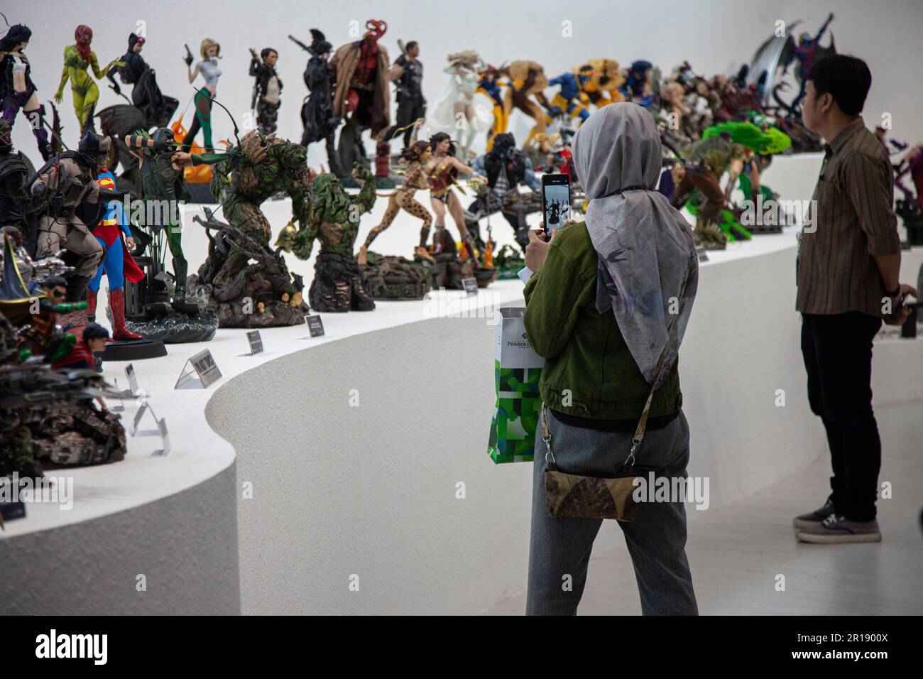 Visitors observe a collection of superhero statues at Statue4Heroes