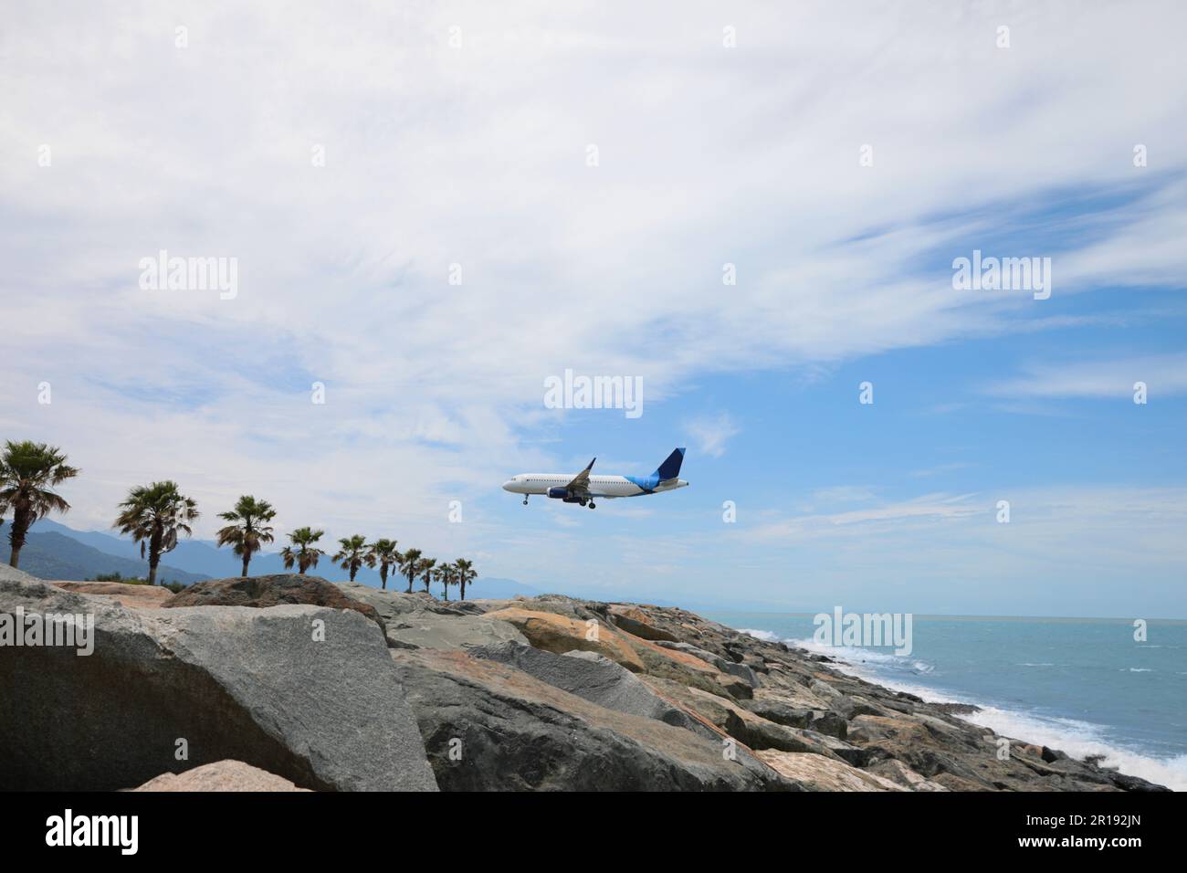 Modern white airplane landing on rocky seacoast Stock Photo - Alamy