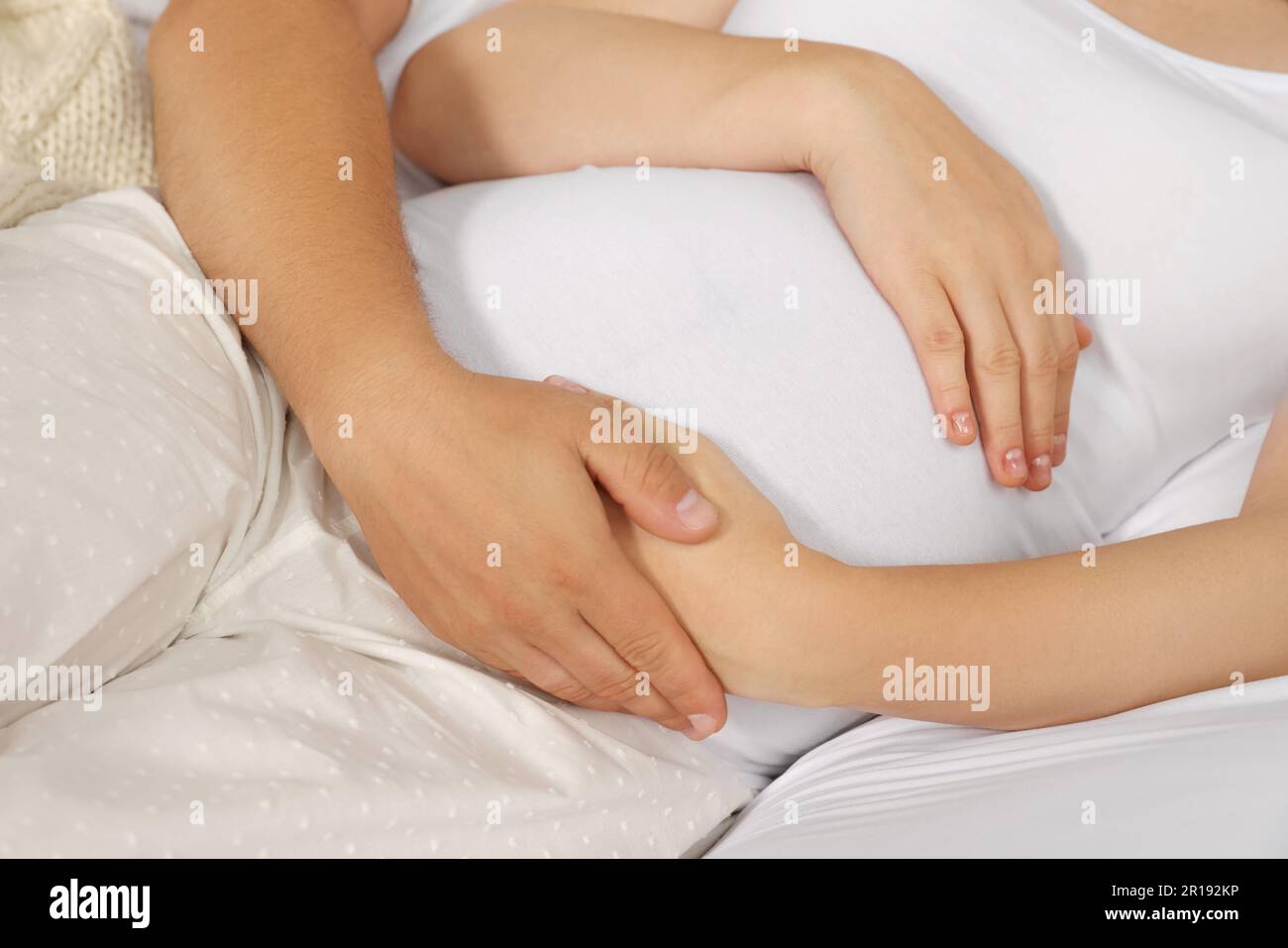 Man hugging his pregnant wife on bed, closeup Stock Photo - Alamy