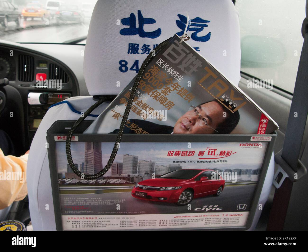 Reading matter, glossy trade magazine, for taxi passengers to read, stored on a seat back pocket holder with advert advertising Honda car, in a cab in Beijing, PRC. China. (125) Stock Photo