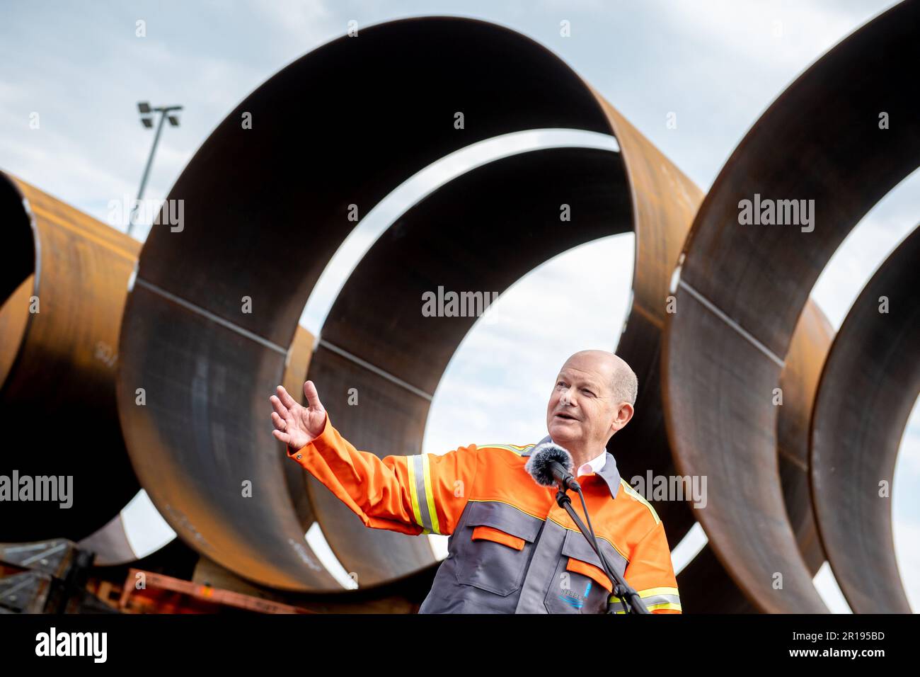 Nordenham, Germany. 12th May, 2023. German Chancellor Olaf Scholz (SPD) speaks to journalists while standing in front of numerous components for the steel foundations of wind turbines. Scholz visited the production of steel foundations, so-called monopiles, for wind turbines in offshore wind farms at Steelwind Nordenham GmbH. Credit: Hauke-Christian Dittrich/dpa/Alamy Live News Stock Photo