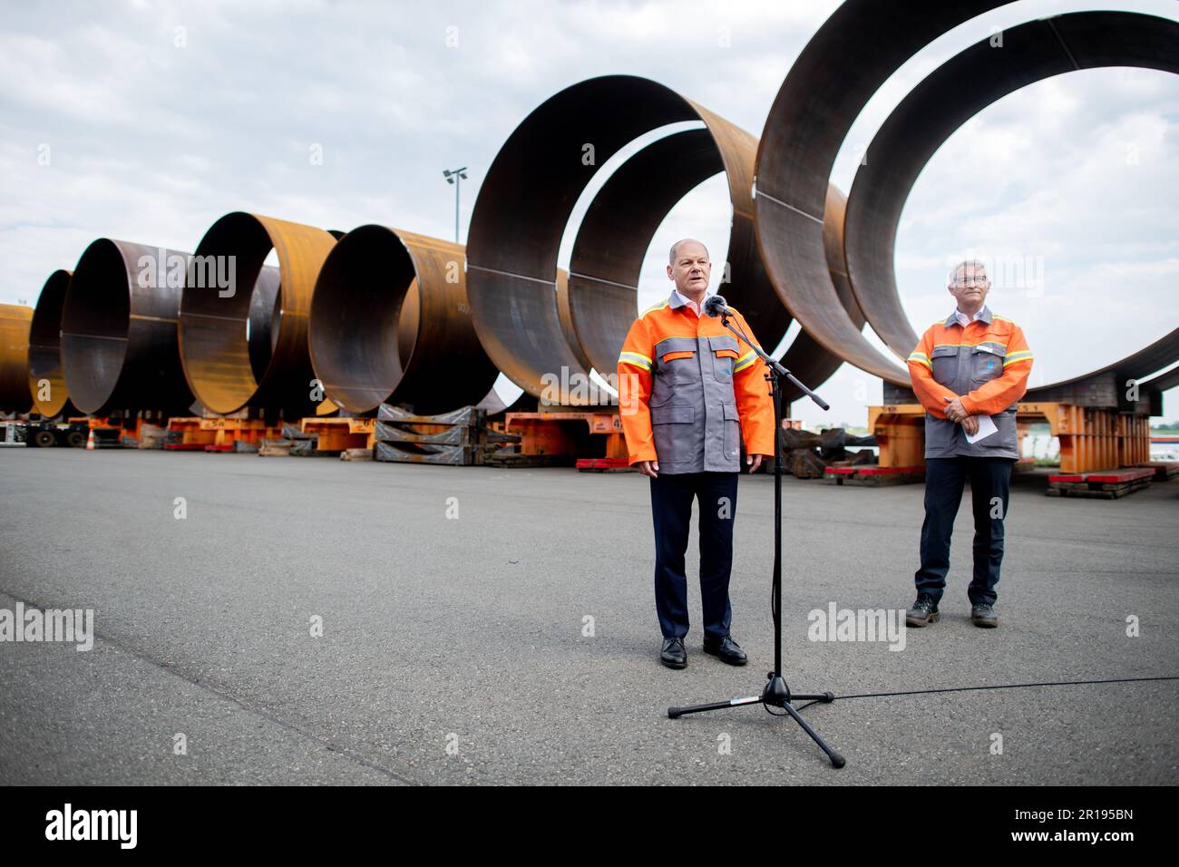 Nordenham, Germany. 12th May, 2023. German Chancellor Olaf Scholz (l, SPD) speaks to journalists while standing with Andreas Liessem, Managing Director of Steelwind Nordenham GmbH, in front of numerous components for the steel foundations of wind turbines. Scholz visited the production of steel foundations, so-called monopiles, for wind turbines in offshore wind farms at Steelwind Nordenham GmbH. Credit: Hauke-Christian Dittrich/dpa/Alamy Live News Stock Photo