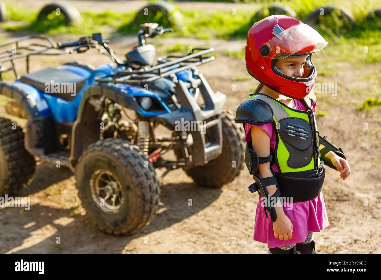 The little girl in protective clothing. Electric quad bike electric car