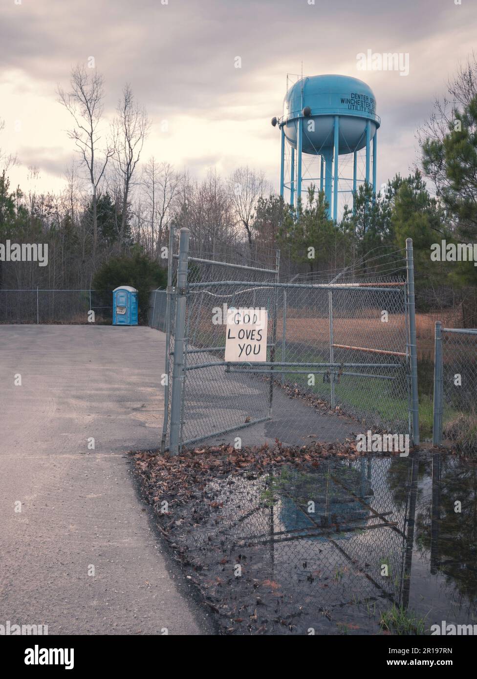 God loves you sign with port-a-potty and water tower Stock Photo