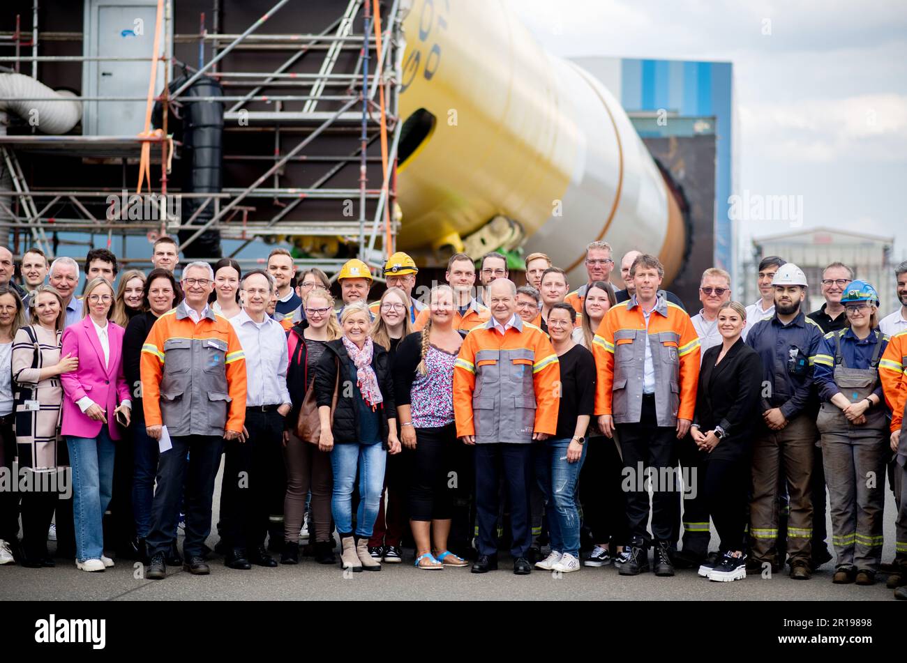 Nordenham, Germany. 12th May, 2023. German Chancellor Olaf Scholz (SPD) stands with numerous employees of Steelwind Nordenham GmbH in front of a component for the steel foundation of a wind turbine at sea. Scholz visited the production of steel foundations, so-called monopiles, for wind turbines in offshore wind farms at Steelwind Nordenham GmbH. Credit: Hauke-Christian Dittrich/dpa/Alamy Live News Stock Photo