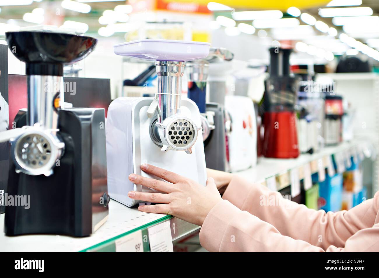 Electric meat grinder in the buyer hand in the store Stock Photo