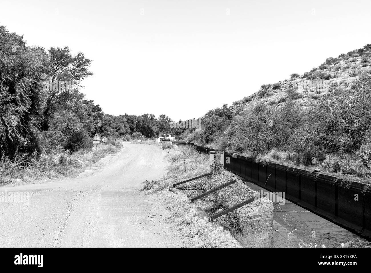 The road and irrigation canal between Brandboom and Boegoeberg Dam in the Northern Cape Province. Monochrome Stock Photo
