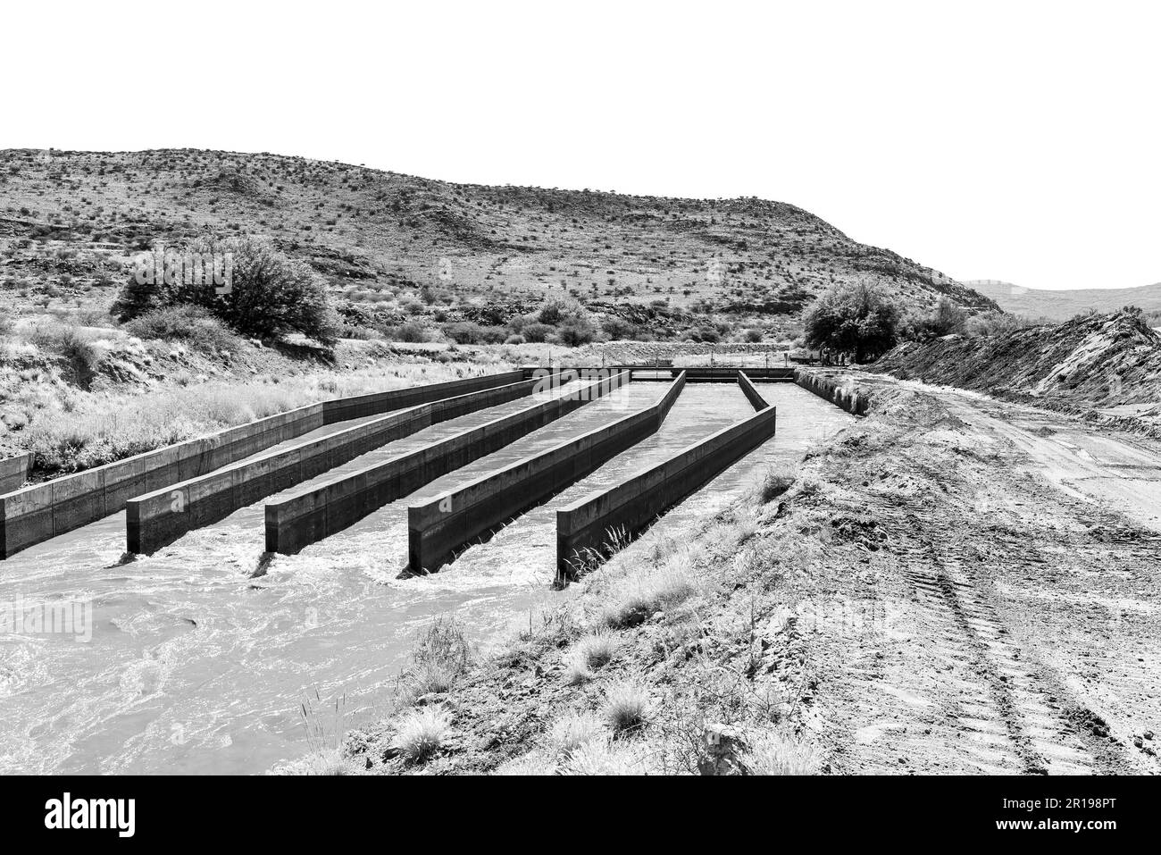 A silt buffer dam in the irrigation canal between Brandboom and Boegoeberg Dam in the Northern Cape Province. Monochrome Stock Photo