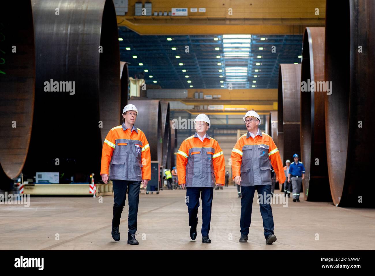 Nordenham, Germany. 12th May, 2023. Jonathan Weber (l-r), member of the Executive Board of Dillinger Hüttenwerke AG, German Chancellor Olaf Scholz (SPD) and Andreas Liessem, Managing Director of Steelwind Nordenham GmbH, walk through a production hall at Steelwind Nordenham GmbH, where steel foundations for offshore wind turbines are manufactured. Scholz visited the production of steel foundations, so-called monopiles, for wind turbines in offshore wind farms at Steelwind Nordenham GmbH. Credit: Hauke-Christian Dittrich/dpa/Alamy Live News Stock Photo