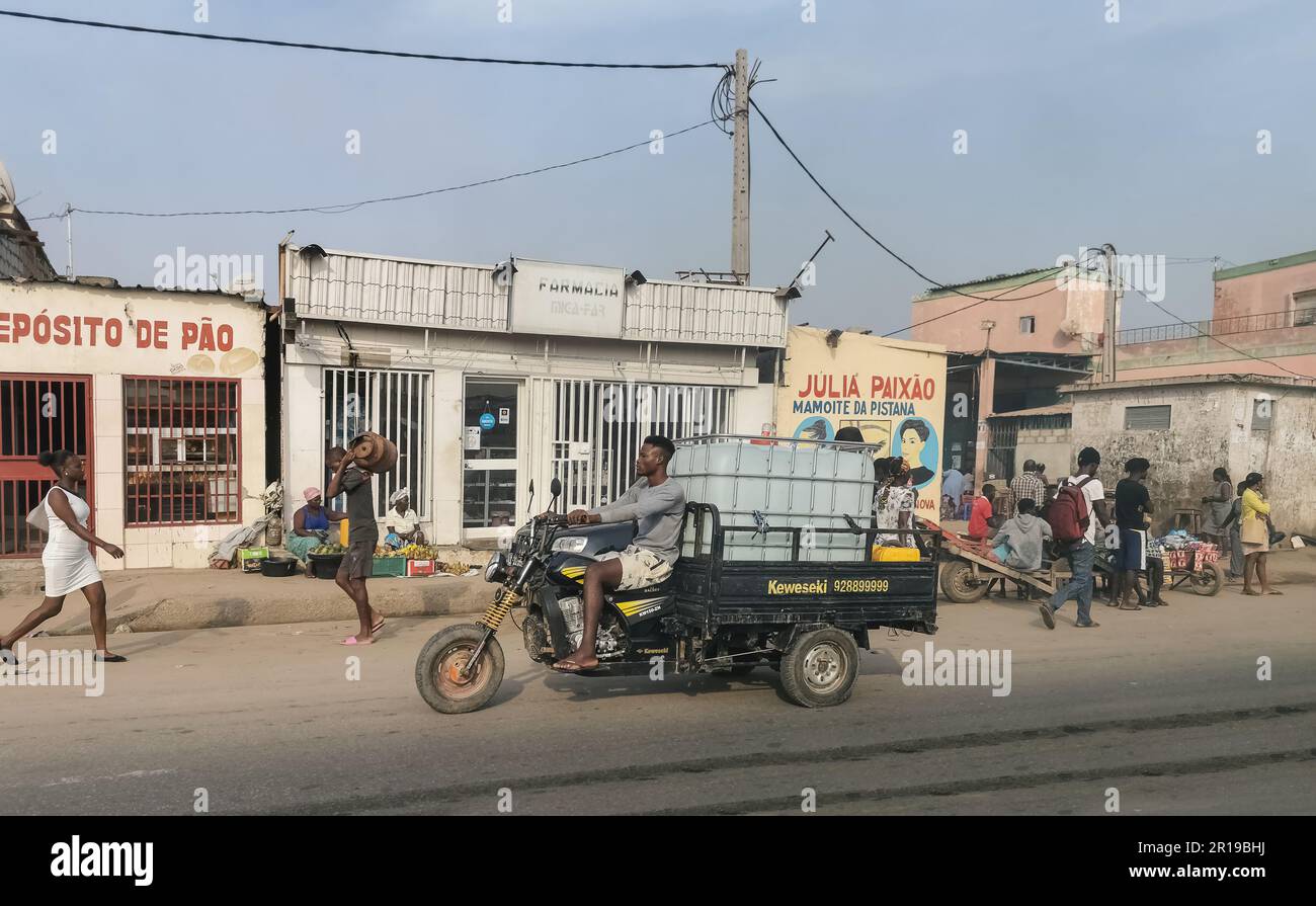 Luanda Angola - 12 16 2022: View at the Luanda capital city, african metropolis lifestyle, with people, moto-boy transporting water and buildings on g Stock Photo