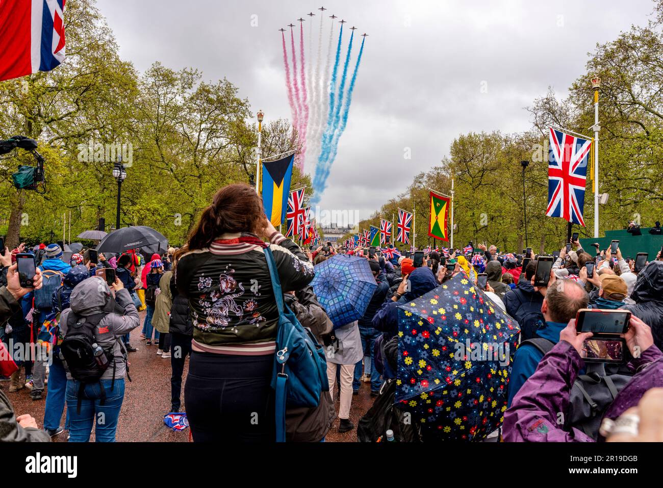 People Standing In The Mall Taking Photos Of The Red Arrows Fly Past After The Coronation of King Charles III, London, UK. Stock Photo