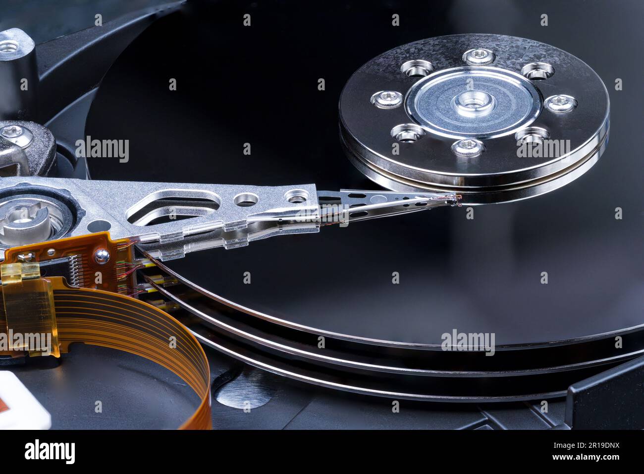 Internal components of a computer hard disk drive used for data storage. Metal disk platters, actuator head and orange ribbon cable. Stock Photo