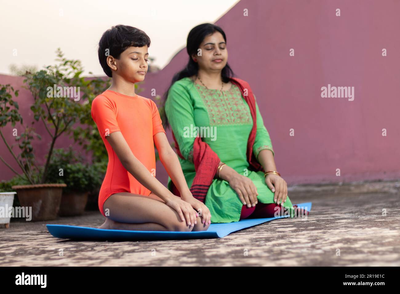 An Indian girl child with mother practicing Vajrasana yoga on yoga mat ...