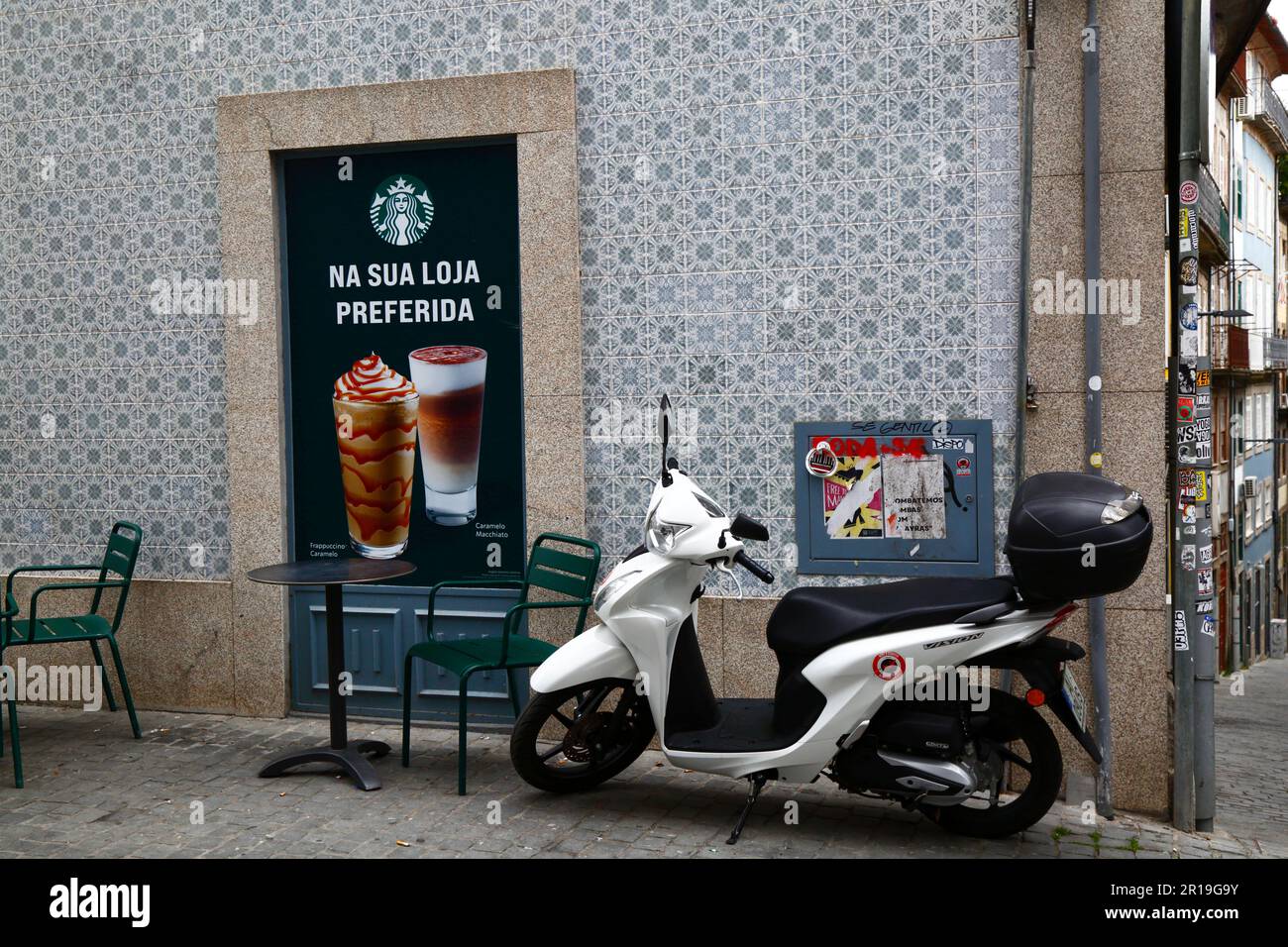 White Honda Vision 110 motor scooter parked on side street next to Starbucks coffee cafe on Praça da Liberdade, Porto / Oporto, Portugal Stock Photo