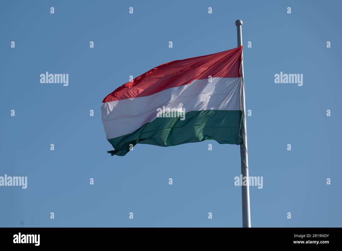 National flag of Hungary flying from a flagpole against a blue sky Stock Photo