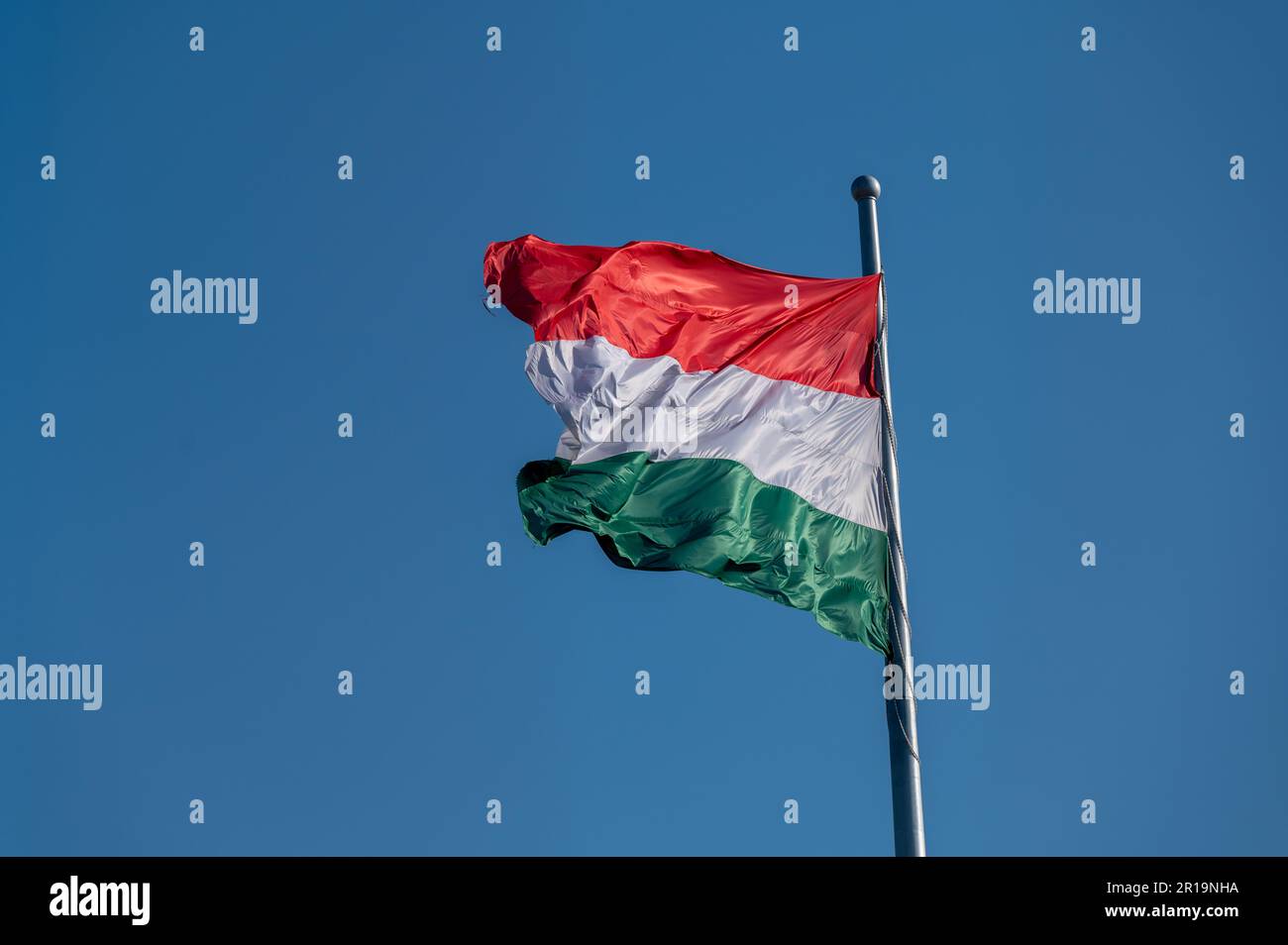 National flag of Hungary flying from a flagpole against a blue sky Stock Photo