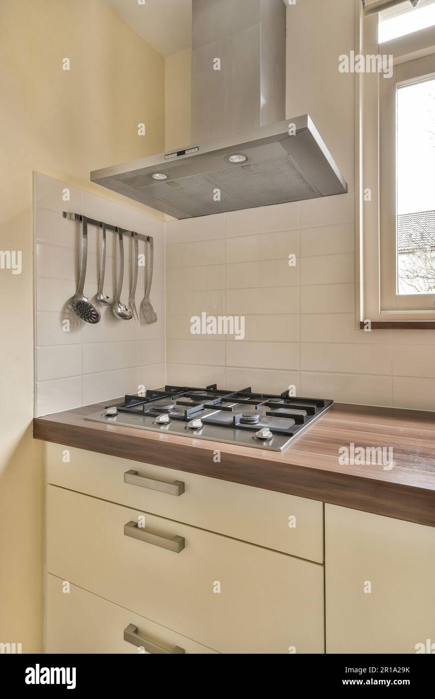 a kitchen with some uts hanging on the wall and an oven hood in the window  over the stovetop Stock Photo - Alamy