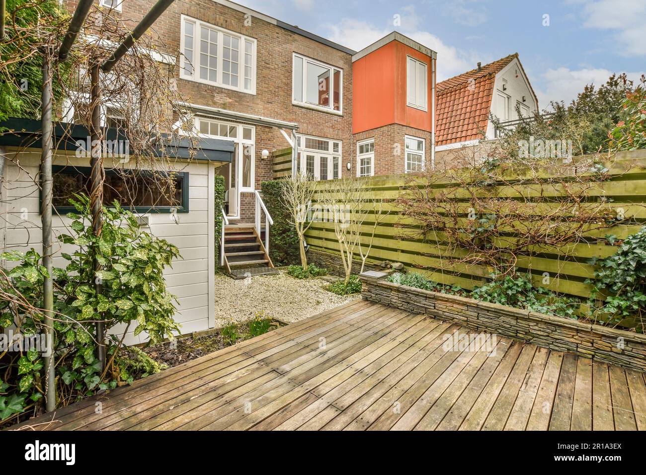 a backyard area with wooden decking and brick houses in the back, on a ...