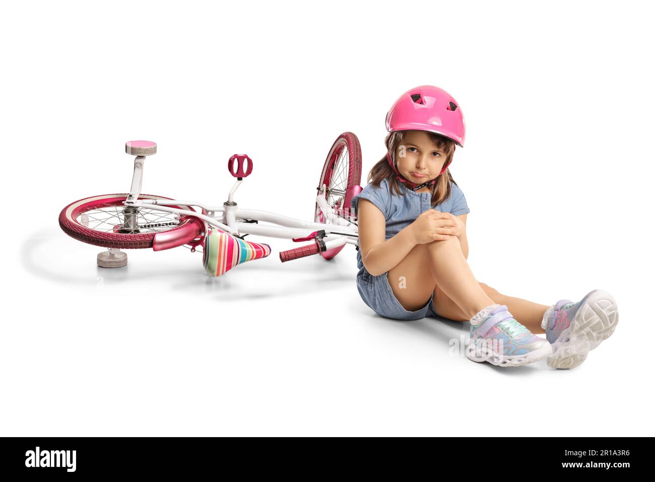 Little girl wearing a bicycle holding her injured knee and sitting on