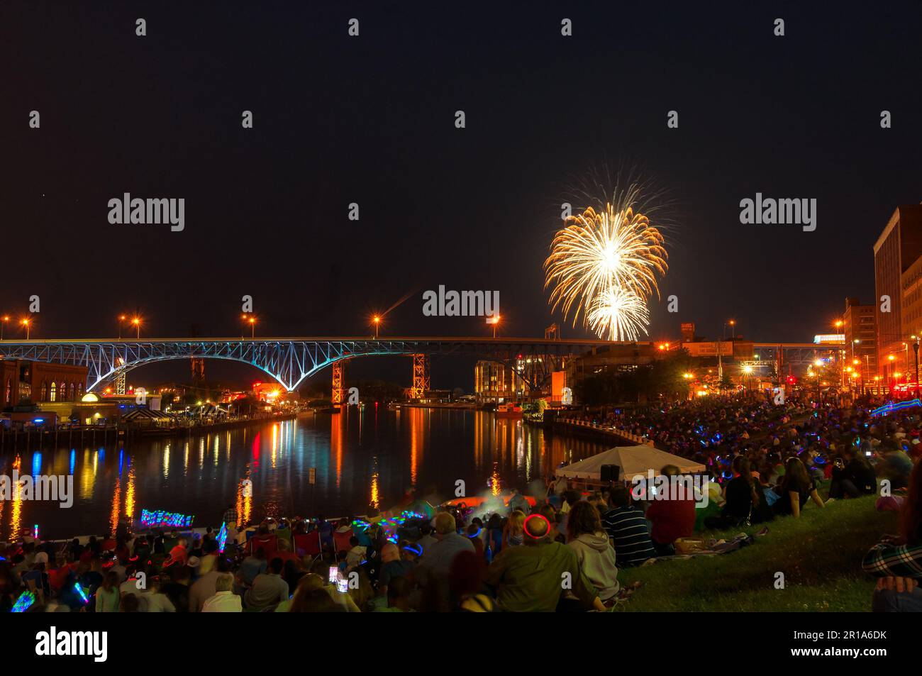 Throngs of spectators gather along the banks of the Cuyahoga River to