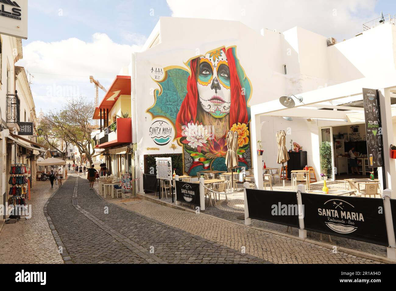A brightly coloured mural of a woman on a restaurant wall, Old Town Lagos, Algarve, Portugal Stock Photo