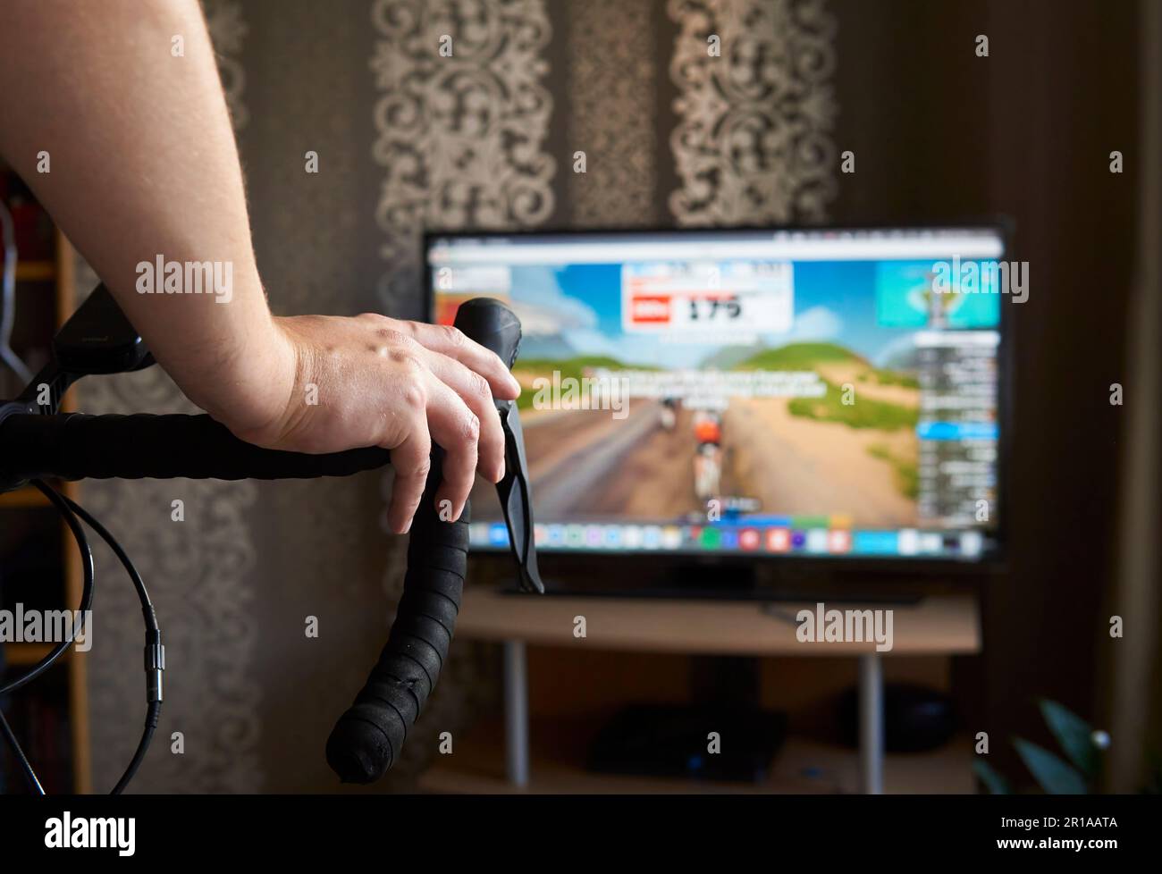 Cyclist is training on the bike with a TV doing online cycling