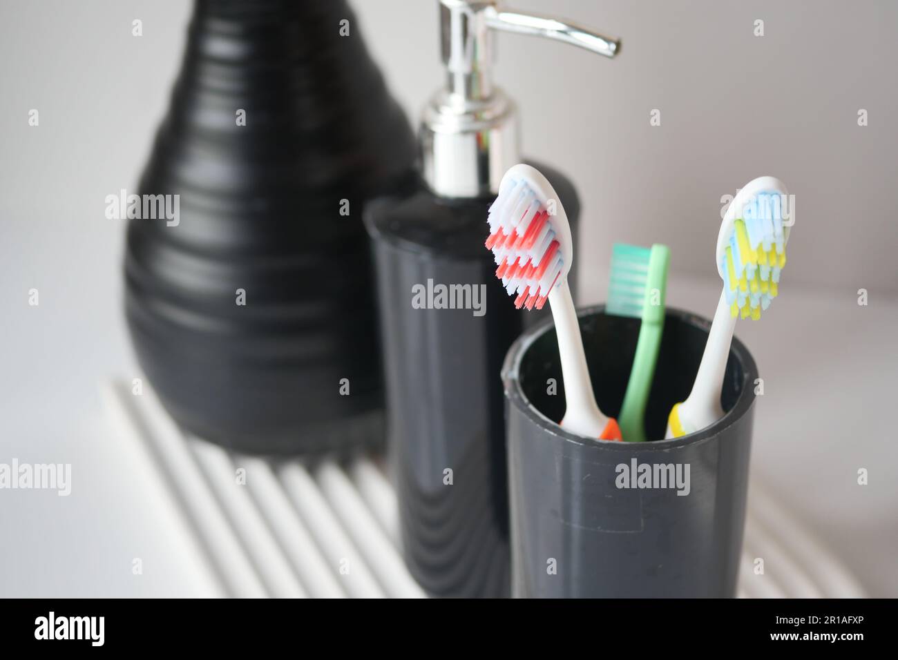 colorful toothbrushes in white mug against a wall Stock Photo - Alamy