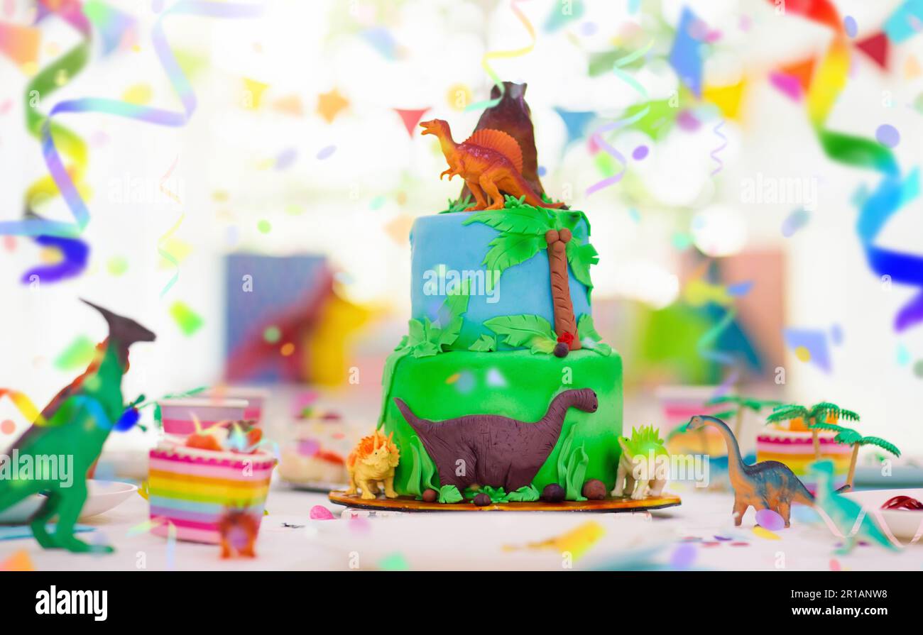 Kids birthday party. Dinosaur theme layer cake. Children event. Decoration for dinosaurs themed celebration. Stock Photo