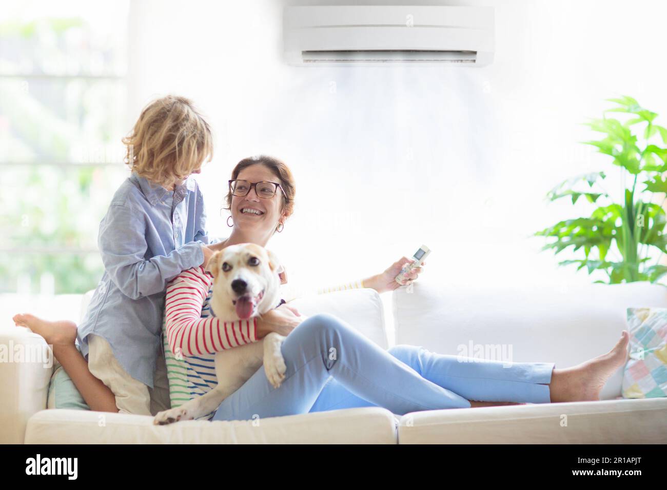 Mother and child with air conditioner remote control. Comfortable