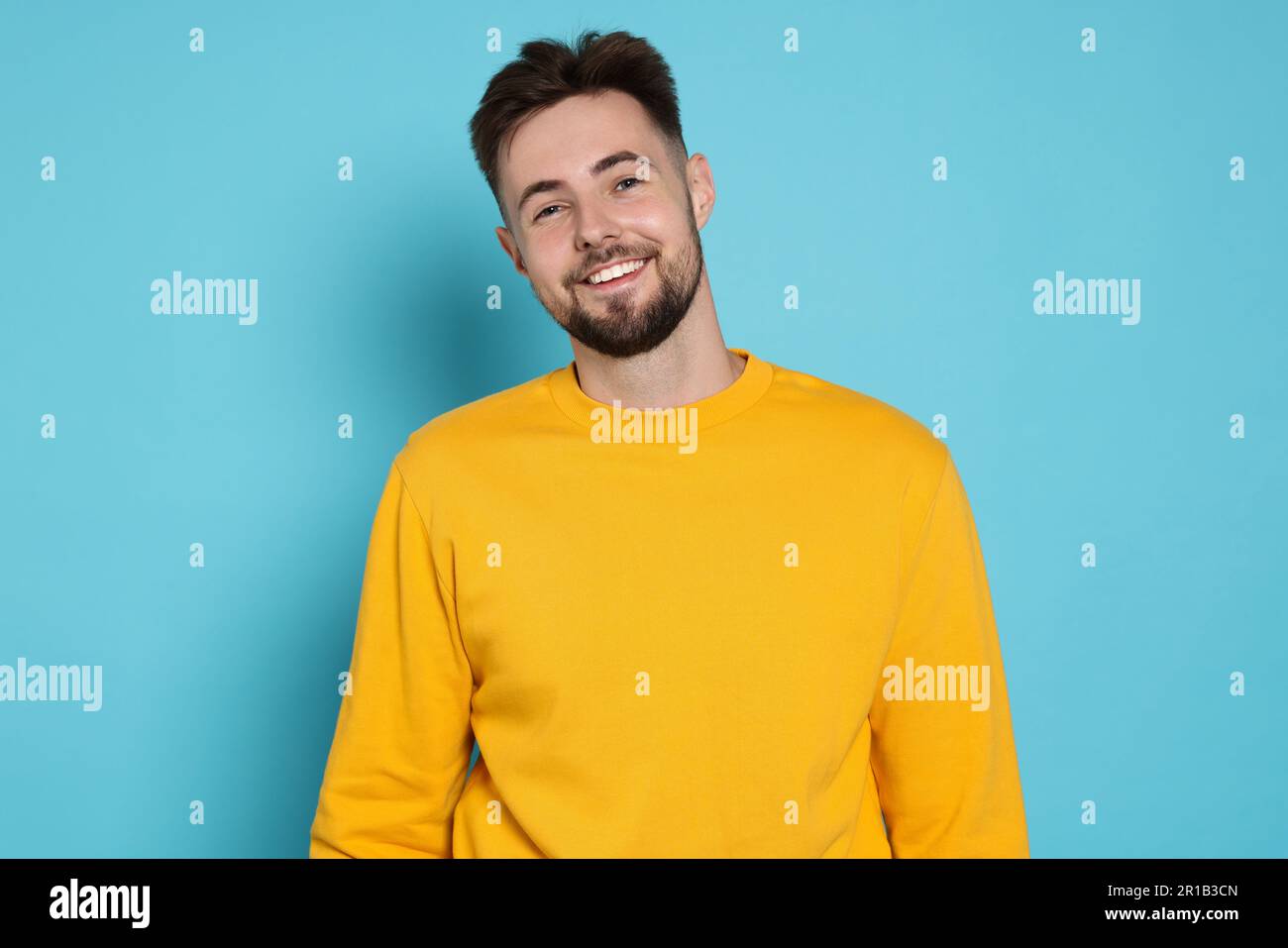 Handsome man in yellow sweatshirt on light blue background Stock Photo