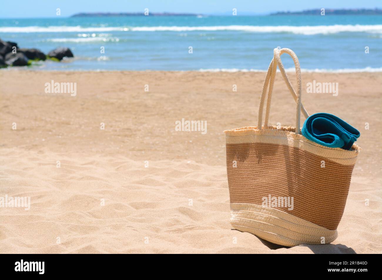 Soft blue towel in beach bag on sand near sea, space for text Stock ...