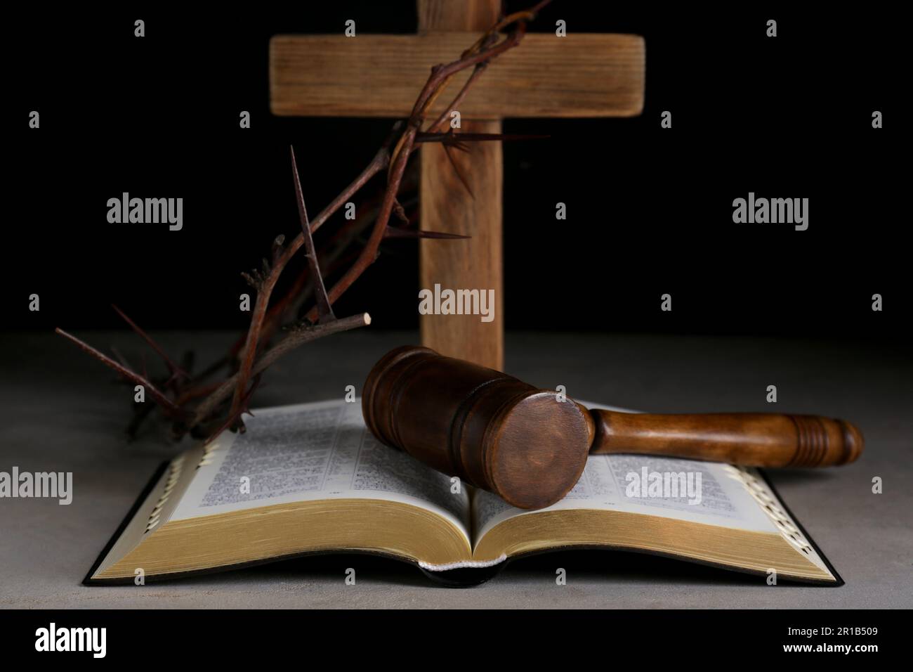 Judge gavel, bible, wooden cross and crown of thorns on grey table