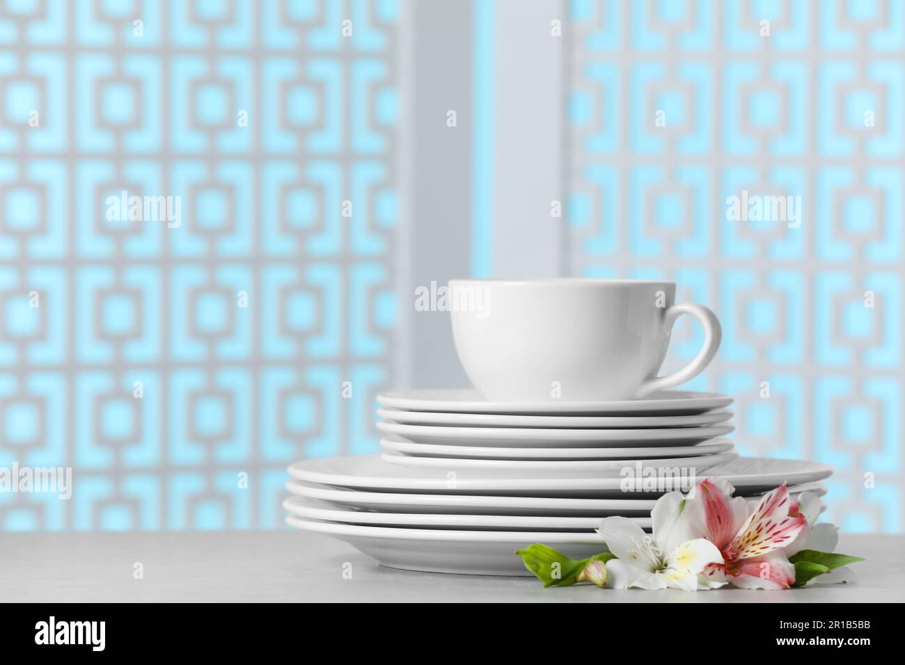Set of clean dishware with flowers on light grey table, space for text ...