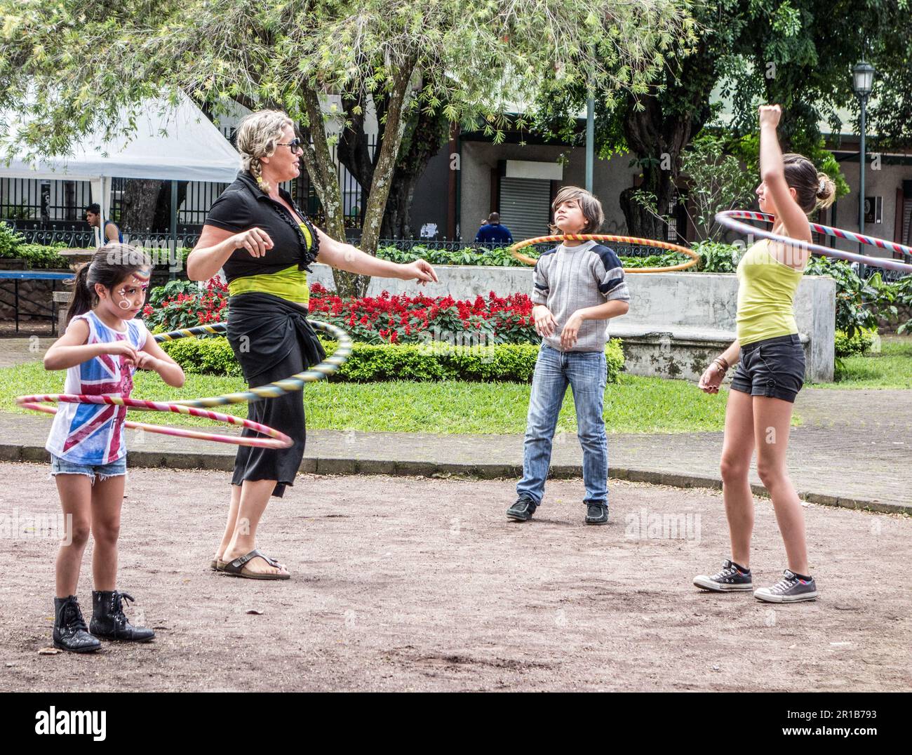 Hula's Rixa Adult woman playing with hula hoops with three kids at a park in San ...