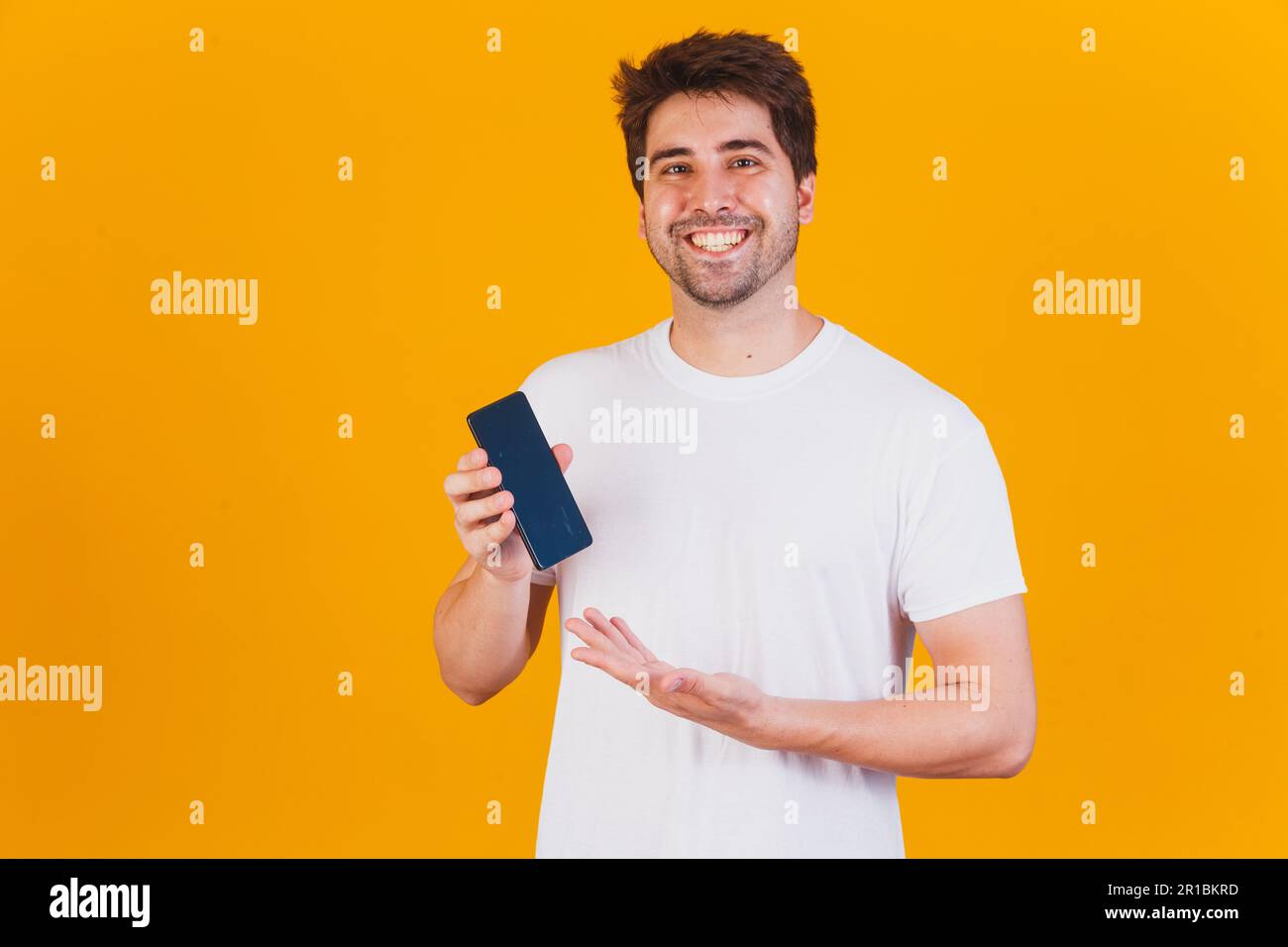 handsome man with cellphone in hands pointing with space for text Stock Photo
