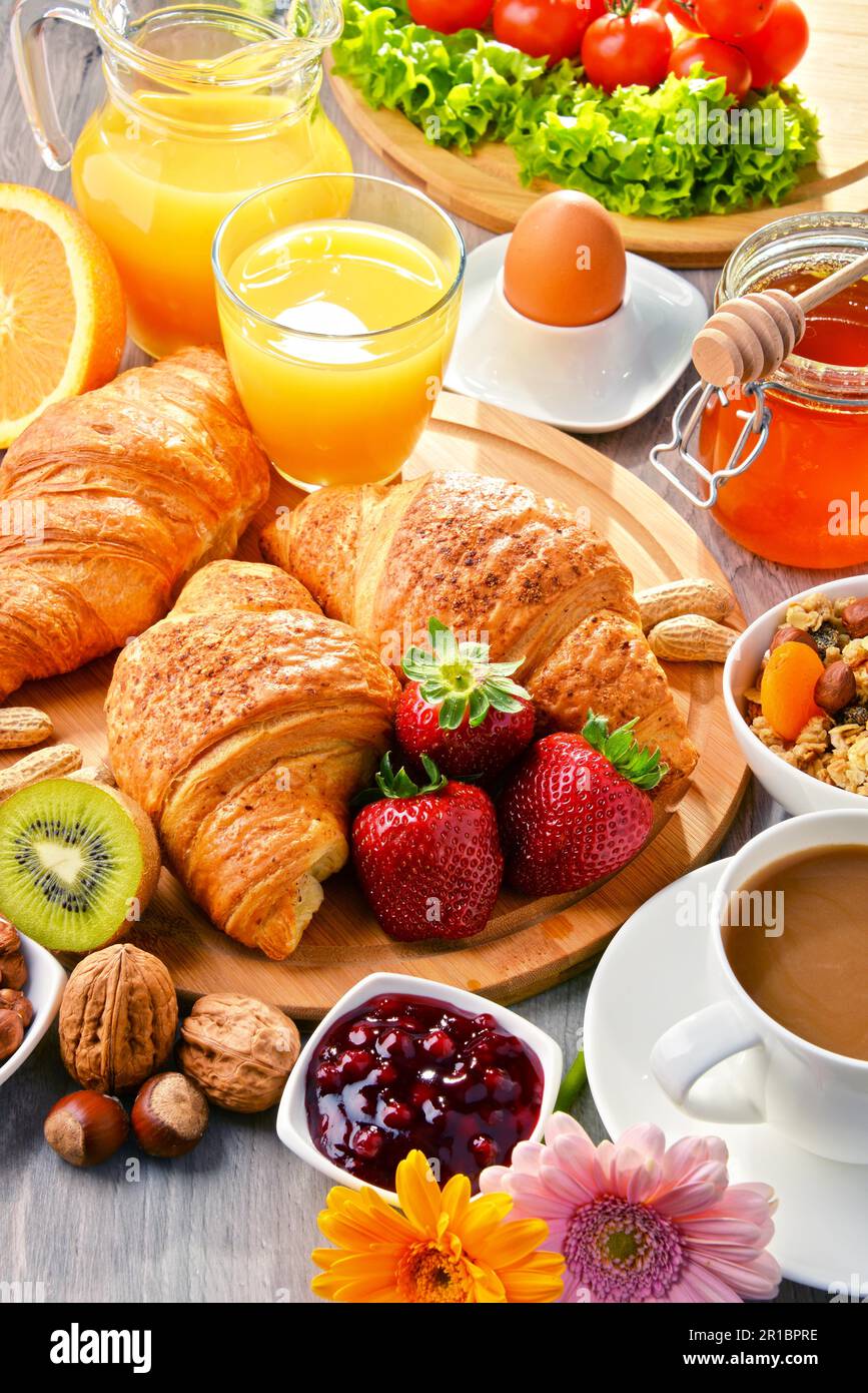 Breakfast consisting of croissants, coffee, fruits, orange juice