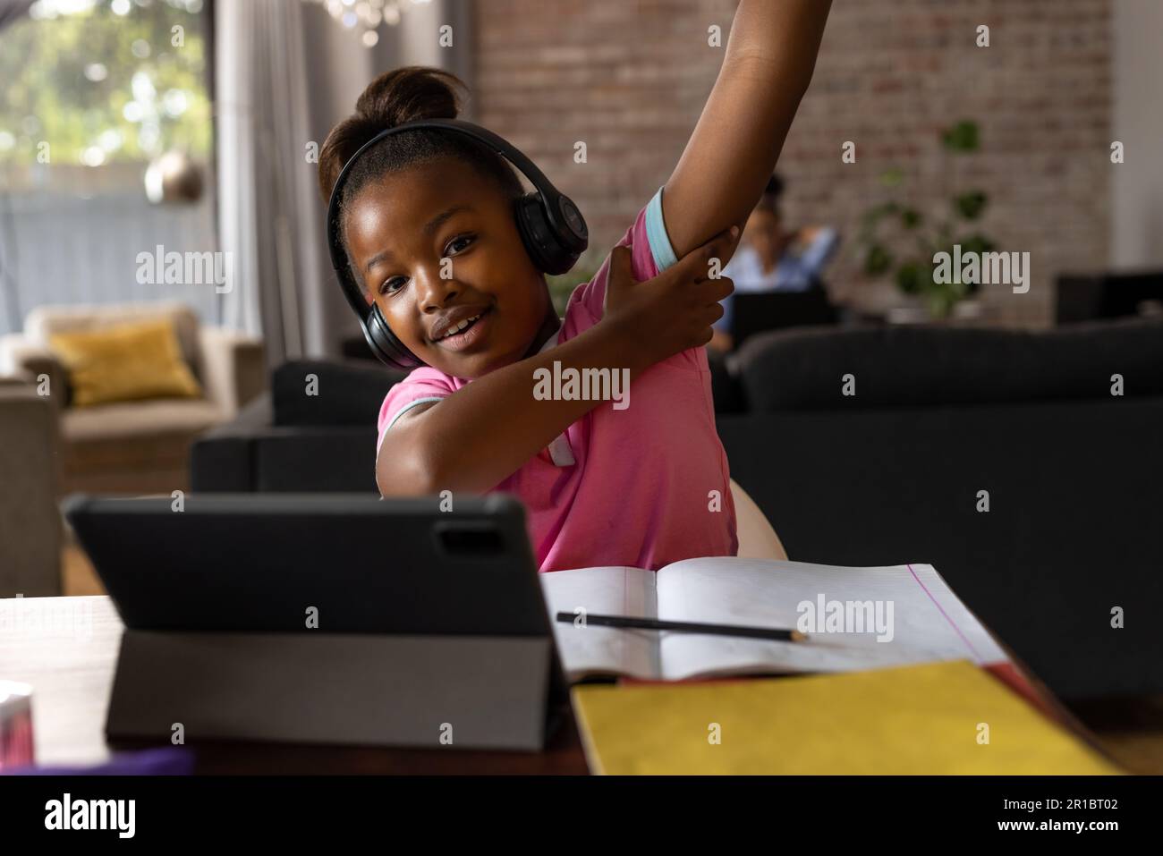 Happy african american girl wearing headphones raising hand during ...