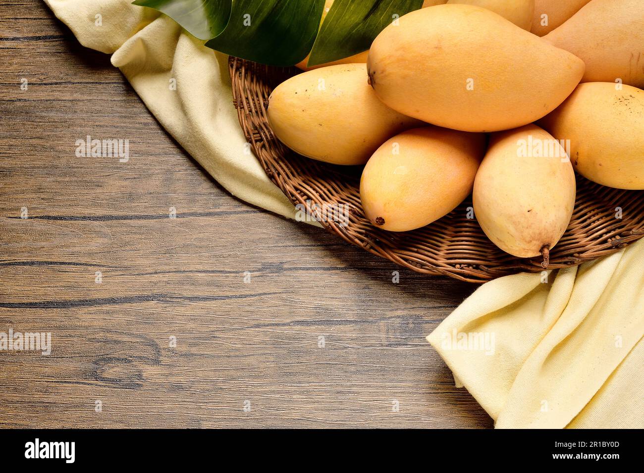 Top Views Many mangoes in wicker basket on wooden table background.Thai