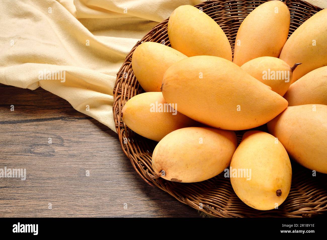 Top Views Many mangoes in wicker basket on wooden table background.Thai