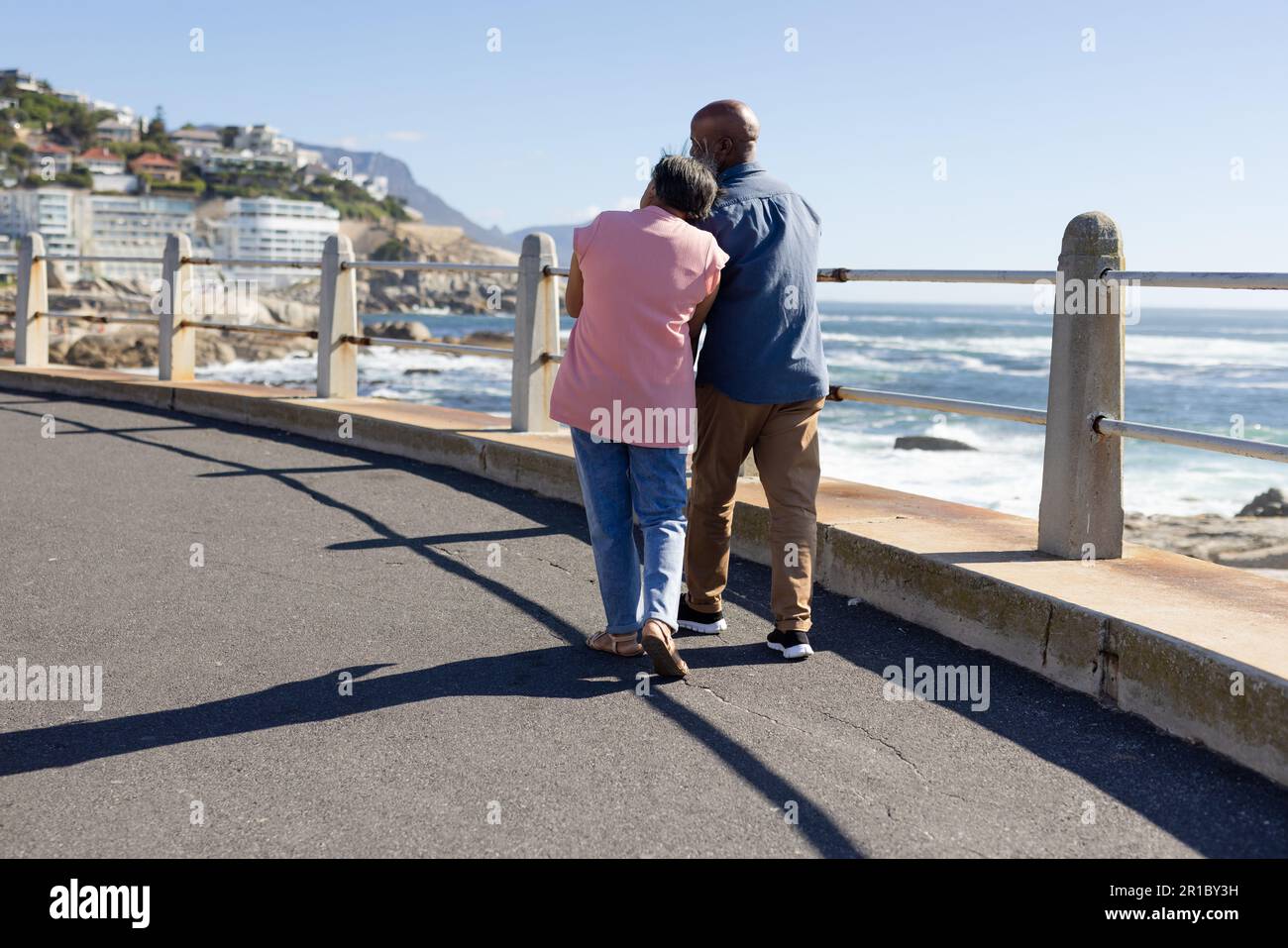 Happy senior african american couple walking and embracing on promenade ...