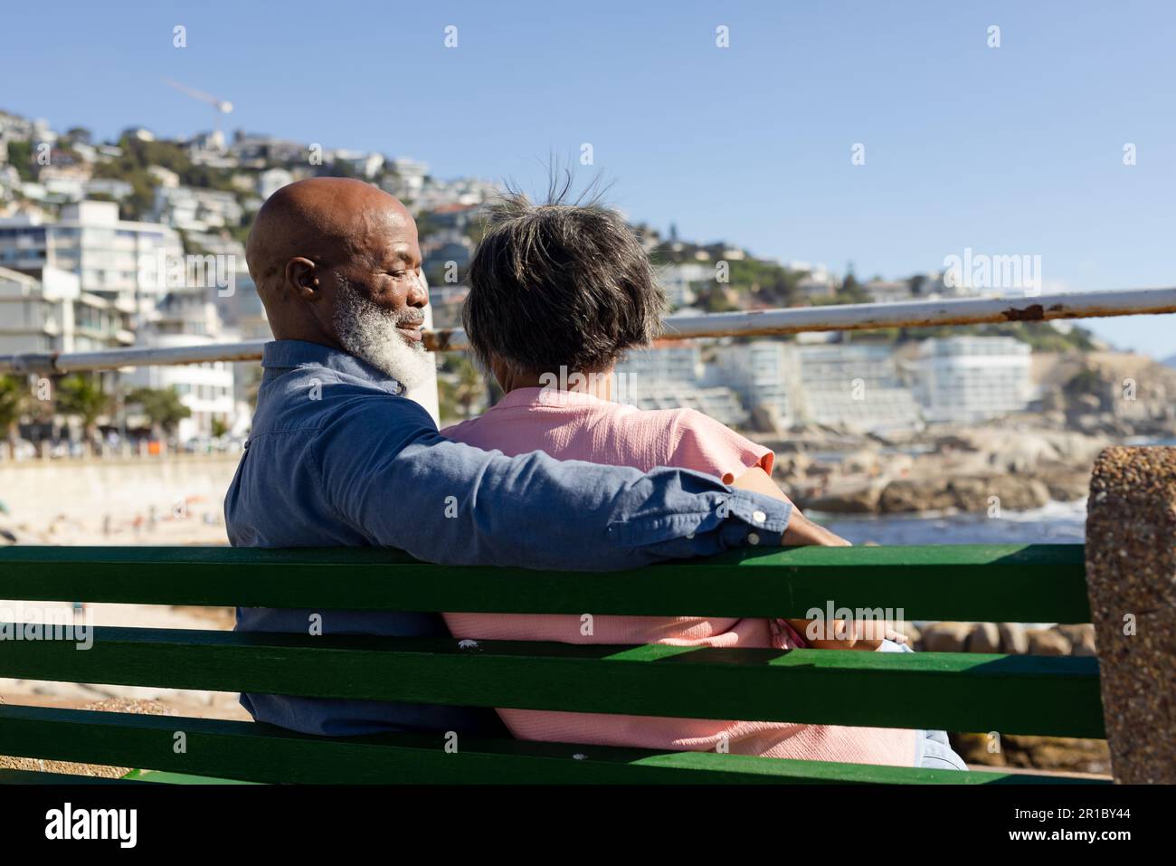 Senior african american couple sitting on bench and embracing on ...