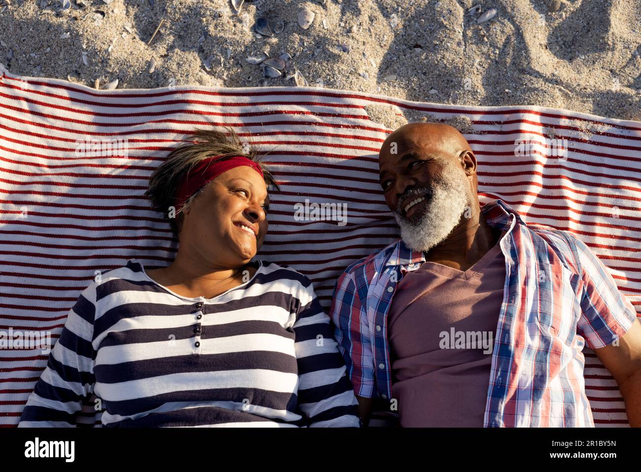 Happy senior african american couple lying on towels at beach Stock ...