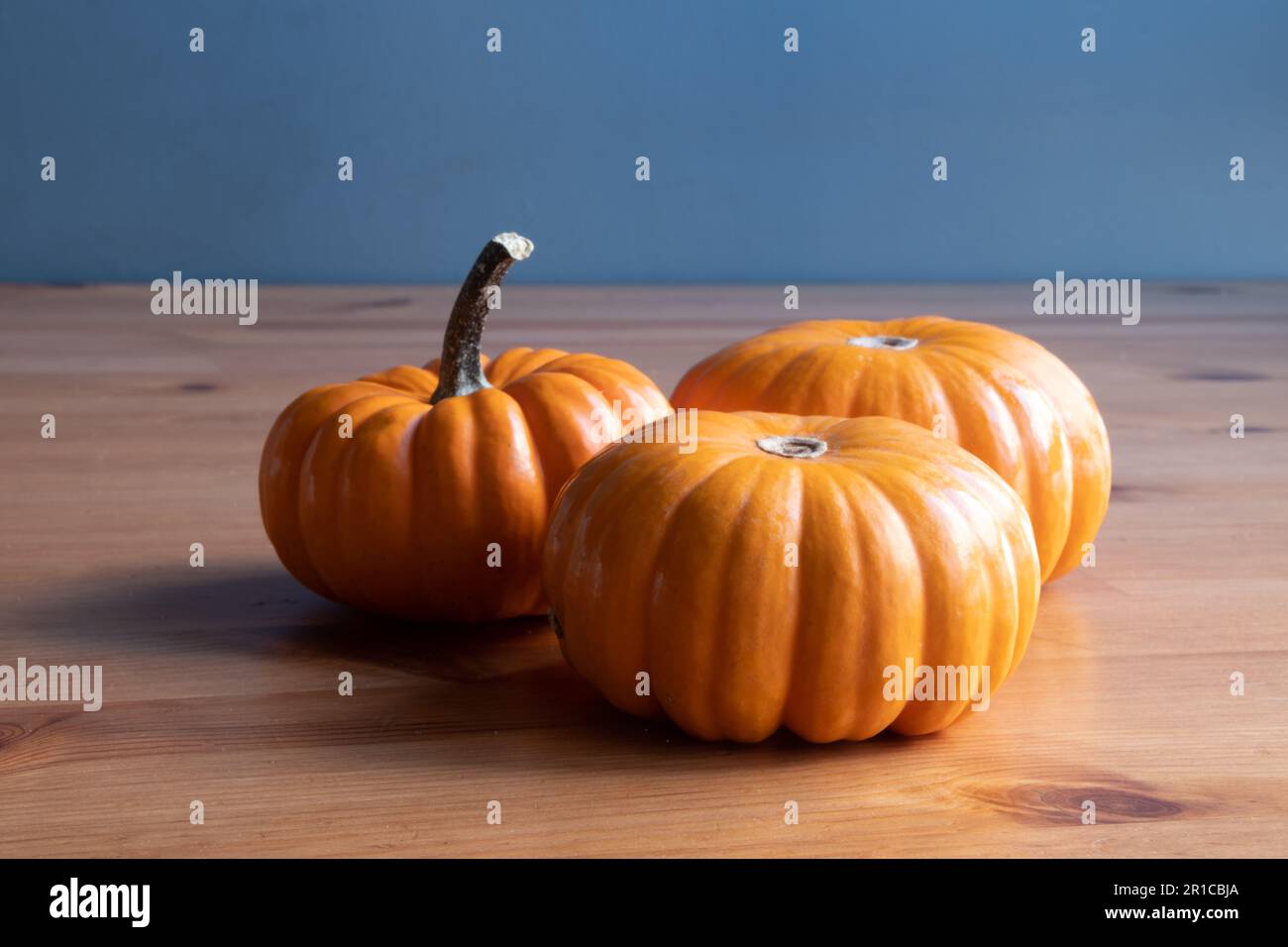 Small orange pumpkins on wooden table background. Front view of three small pumpkins Stock Photo