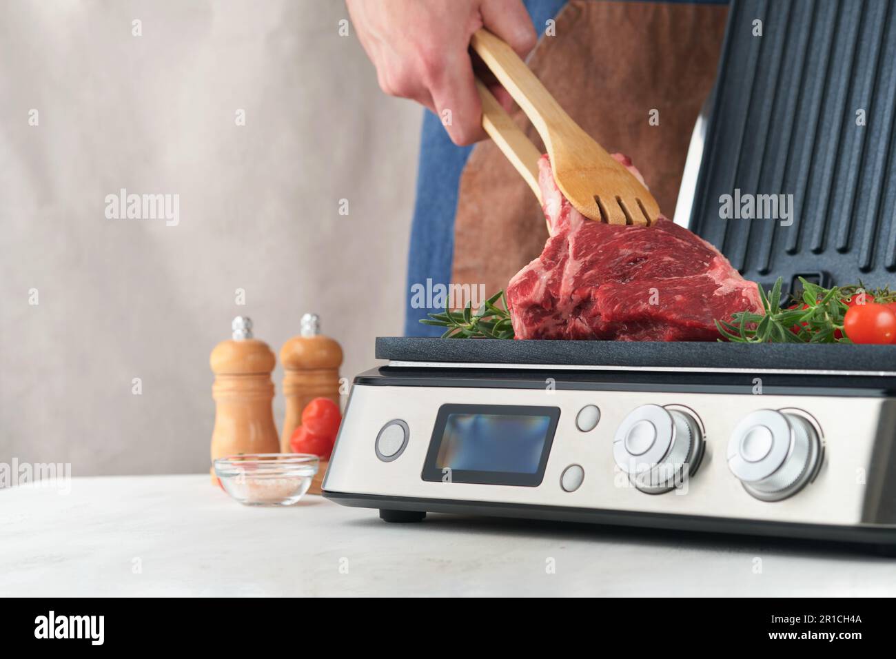 Raw prime steaks on electric grill. Chef male hand holding steak Ribeye