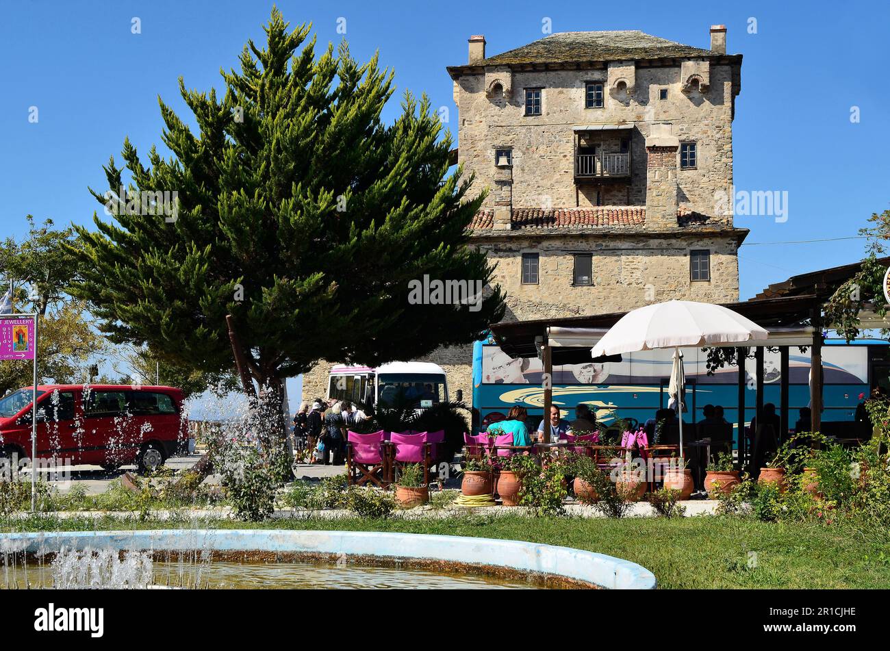 Ouranoupolis, Greece - September 29, 2011: Unidentified tourists in a restaurant in front of the Prosphorios-Tower, the landmark of the small village Stock Photo