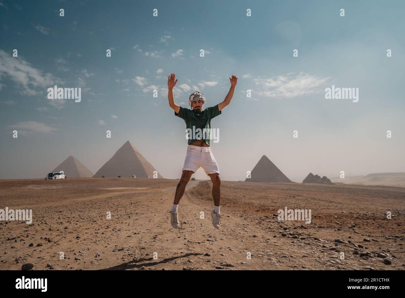 young man with a turban jumps in the desert with the pyramids in the background. Cairo. Egypt Stock Photo